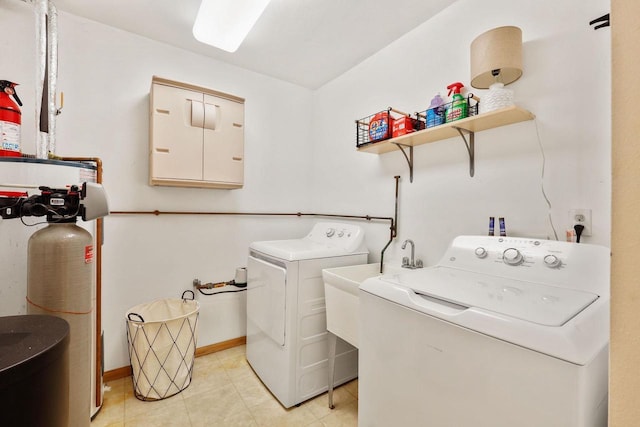 washroom with light tile patterned floors, separate washer and dryer, baseboards, and laundry area