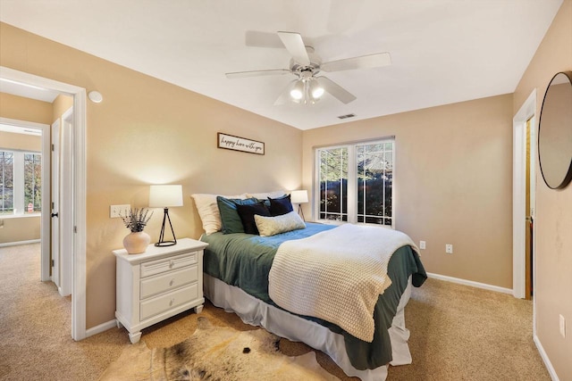 bedroom with baseboards, light colored carpet, ceiling fan, and visible vents