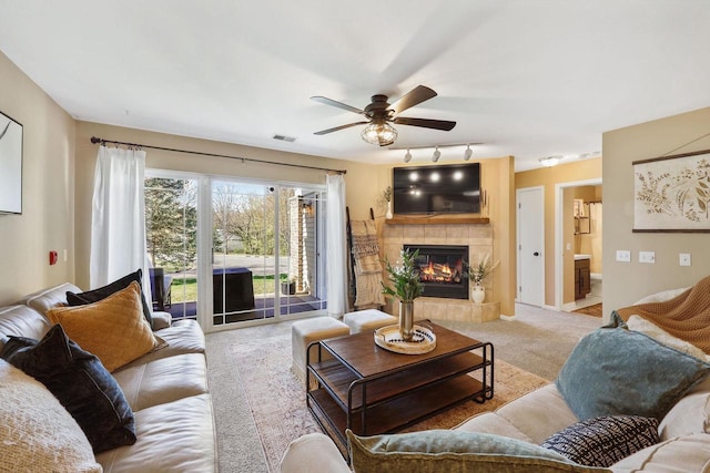 carpeted living area with visible vents, rail lighting, ceiling fan, and a fireplace