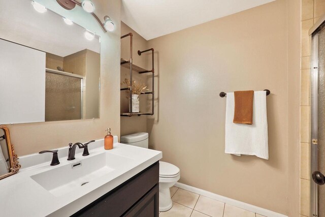 full bath featuring a stall shower, vanity, tile patterned floors, baseboards, and toilet