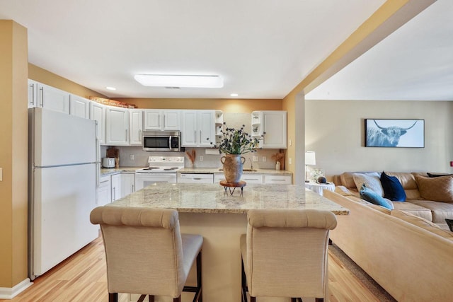 kitchen featuring decorative backsplash, light wood-type flooring, white cabinets, open floor plan, and white appliances