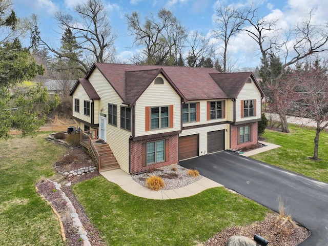 view of front facade featuring brick siding, driveway, a garage, and a front lawn