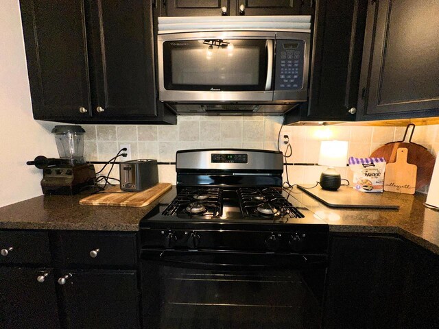kitchen with dark cabinets, stainless steel microwave, dark countertops, black gas stove, and decorative backsplash