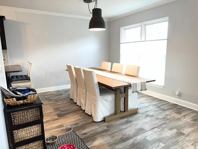 dining room with crown molding, wood finished floors, and baseboards