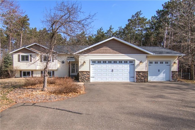 view of front of house with a garage, aphalt driveway, and stone siding