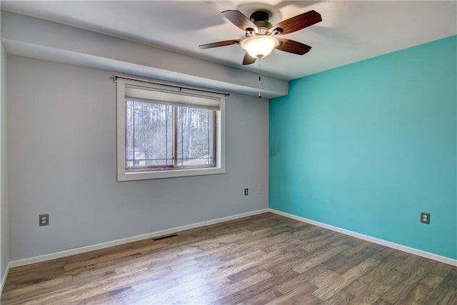 empty room with visible vents, ceiling fan, baseboards, and wood finished floors