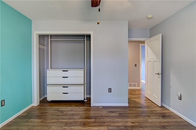unfurnished bedroom with a closet, baseboards, dark wood-style floors, and visible vents