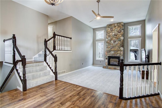 unfurnished living room with baseboards, a fireplace, visible vents, ceiling fan, and wood finished floors