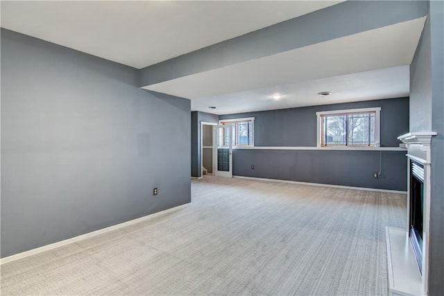 unfurnished living room with a fireplace, baseboards, and carpet floors