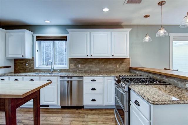 kitchen featuring white cabinets, a peninsula, a sink, and appliances with stainless steel finishes