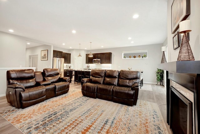 living area with a fireplace, recessed lighting, light wood-style flooring, and baseboards