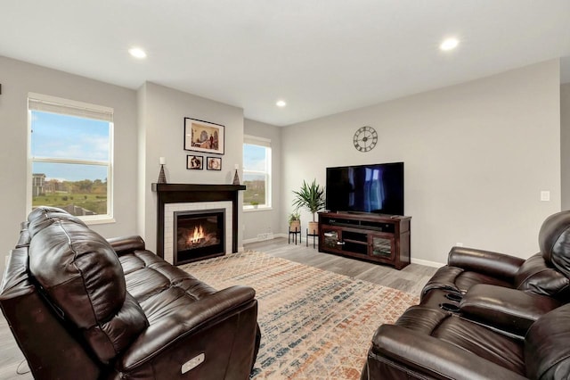 living room featuring a tiled fireplace, baseboards, recessed lighting, and light wood-style floors