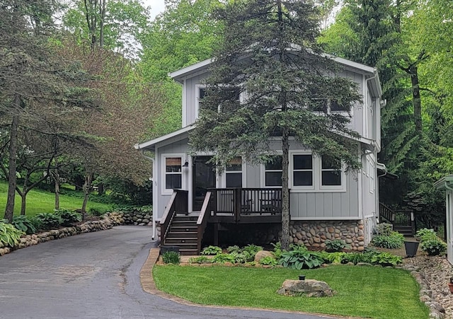 view of front of house featuring stone siding, a front lawn, and board and batten siding
