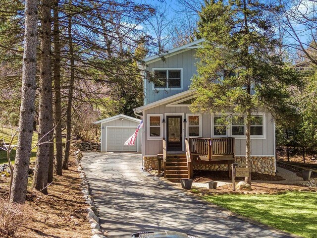 view of front of property featuring concrete driveway, a garage, and an outbuilding