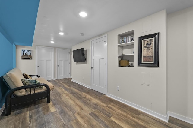 sitting room with wood finished floors, built in shelves, recessed lighting, and baseboards