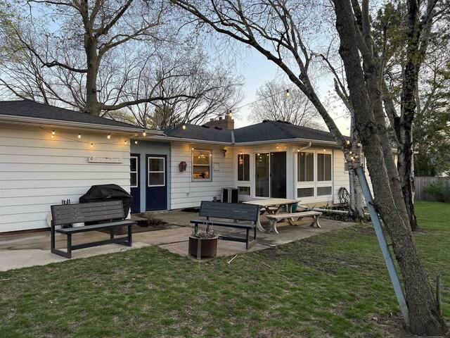 back of property featuring a patio, fence, a chimney, and a lawn