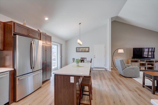 4062 Red Hawk Run, Black Earth, WI 53515 - kitchen featuring light countertops, freestanding refrigerator, a kitchen breakfast bar, light wood finished floors, and vaulted ceiling