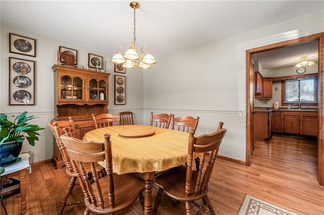 dining room with baseboards, light wood-type flooring, and a chandelier