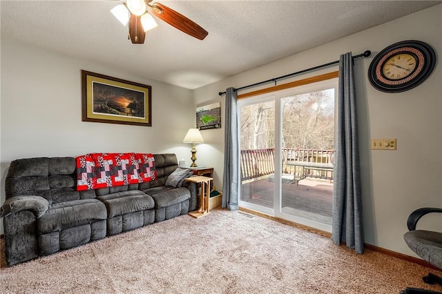 carpeted living room with a textured ceiling, baseboards, and a ceiling fan