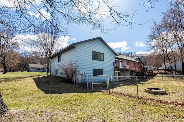 view of side of property featuring a wooden deck, a gate, fence, and a lawn
