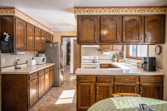 W5384 25th St, Necedah, WI 54646 - kitchen featuring white appliances, a peninsula, light countertops, decorative backsplash, and a sink