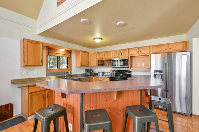 29323 Riverview Ln, Waterford, WI 53185 - kitchen featuring light wood-style floors, a kitchen breakfast bar, a sink, and appliances with stainless steel finishes
