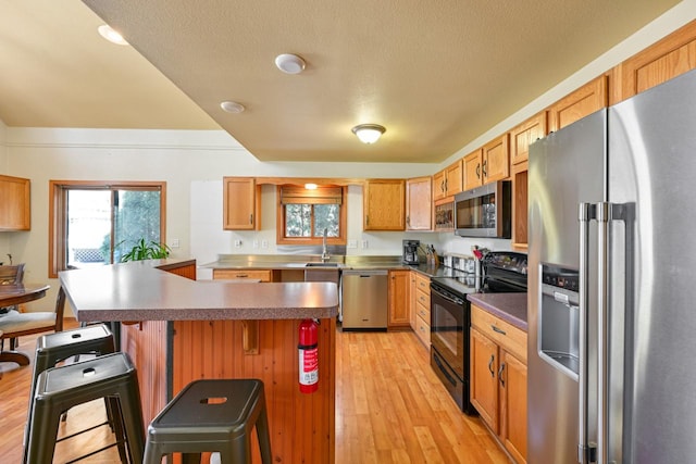 29323 Riverview Ln, Waterford, WI 53185 - kitchen with a center island, light wood-style floors, a kitchen bar, appliances with stainless steel finishes, and a sink