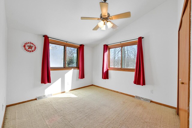 29323 Riverview Ln, Waterford, WI 53185 - carpeted spare room featuring visible vents, baseboards, vaulted ceiling, and a ceiling fan