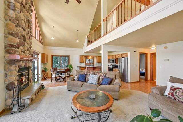 29323 Riverview Ln, Waterford, WI 53185 - living room featuring high vaulted ceiling, light wood-style floors, a stone fireplace, and a ceiling fan