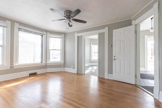 entrance foyer with baseboards, a ceiling fan, crown molding, visible vents, and wood-type flooring