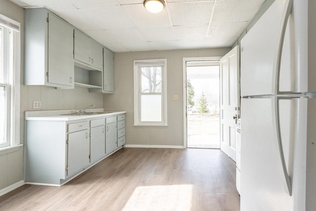 kitchen with light wood-style flooring, a healthy amount of sunlight, freestanding refrigerator, and light countertops