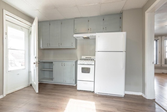 kitchen featuring baseboards, white appliances, under cabinet range hood, gray cabinetry, and wood finished floors