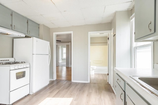 kitchen with light countertops, light wood-style floors, under cabinet range hood, white range with gas cooktop, and gray cabinets