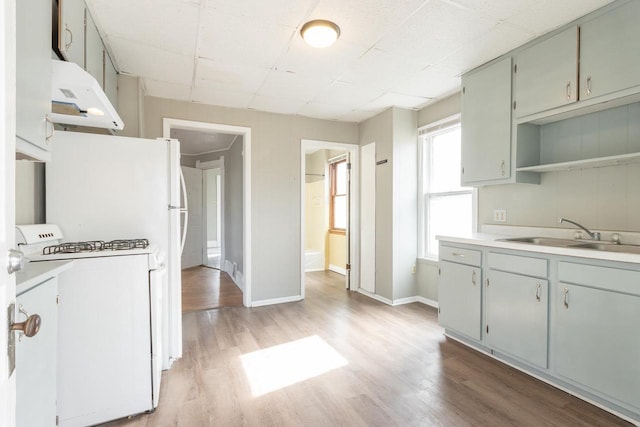 kitchen with light wood-style flooring, light countertops, a sink, and white gas stove