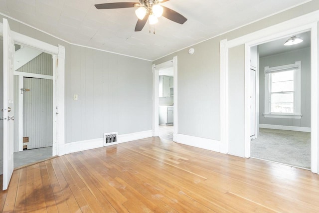 empty room with ornamental molding, visible vents, ceiling fan, and baseboards