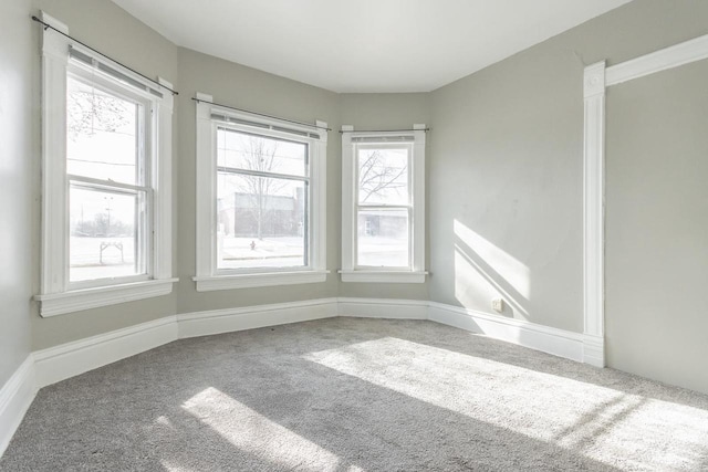 unfurnished room with baseboards, plenty of natural light, and carpet