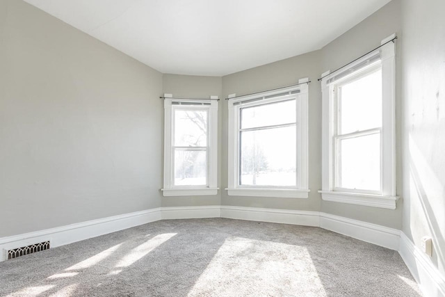 carpeted empty room with visible vents, baseboards, and plenty of natural light