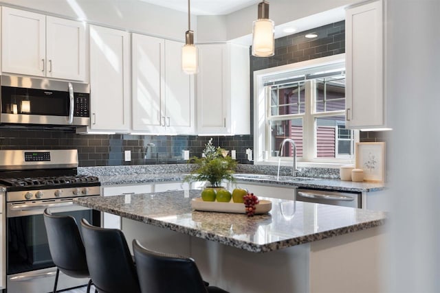 kitchen with stainless steel appliances, a kitchen breakfast bar, stone counters, backsplash, and white cabinets