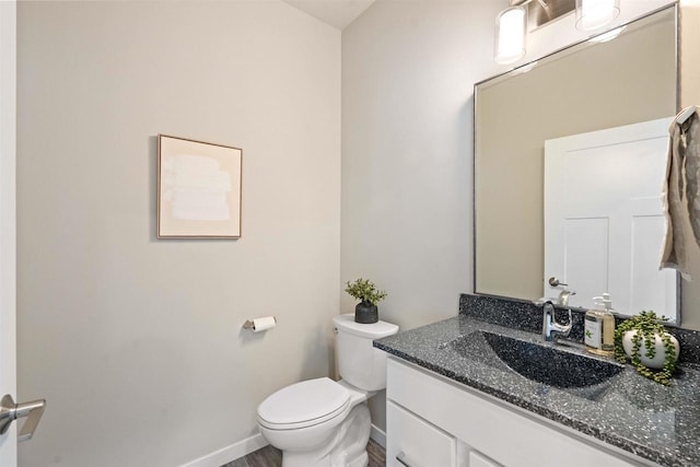 half bath featuring toilet, wood finished floors, vanity, and baseboards