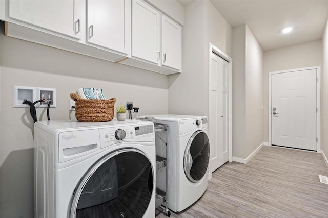 washroom with light wood-style flooring, visible vents, baseboards, washer and clothes dryer, and cabinet space