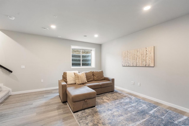 living area featuring baseboards, light wood-type flooring, stairs, and recessed lighting
