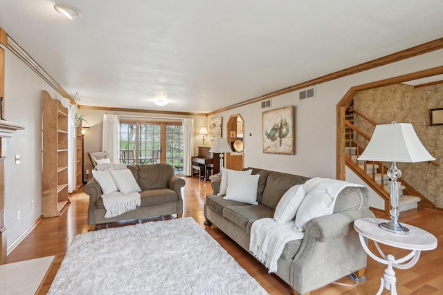 living room featuring ornamental molding, stairs, visible vents, and wood finished floors