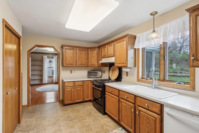 kitchen with gas stove, under cabinet range hood, light countertops, dishwasher, and a sink