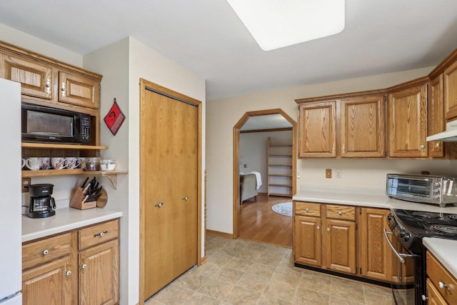 kitchen with a toaster, black appliances, arched walkways, and light countertops