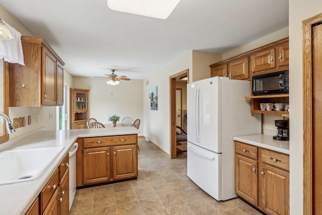 kitchen with freestanding refrigerator, a sink, black microwave, a ceiling fan, and a peninsula