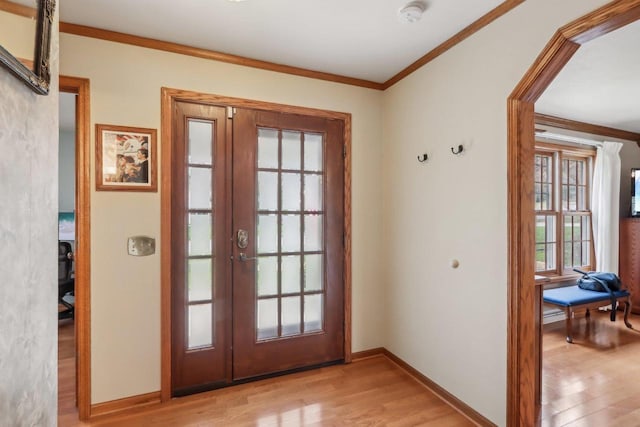 entryway with crown molding, baseboards, and light wood-type flooring