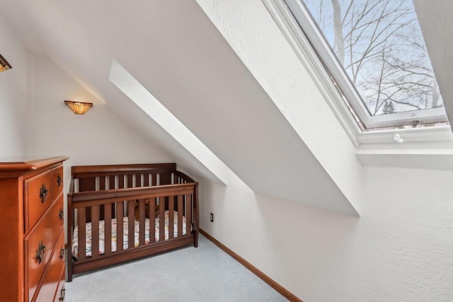carpeted bedroom with a crib, baseboards, and vaulted ceiling with skylight