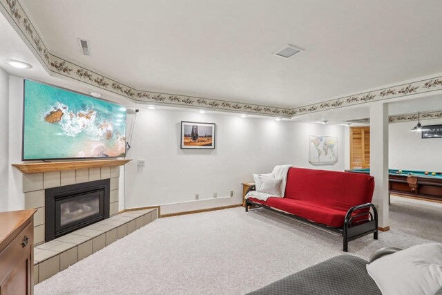 carpeted living room with a tiled fireplace and pool table