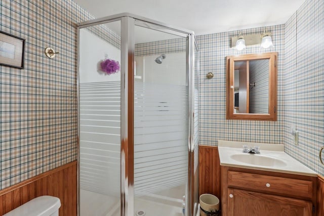 bathroom featuring vanity, a shower stall, and wallpapered walls