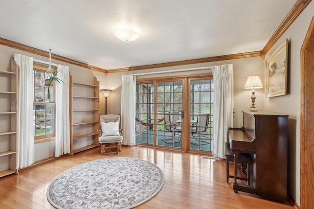 living area featuring wood finished floors, a healthy amount of sunlight, and ornamental molding